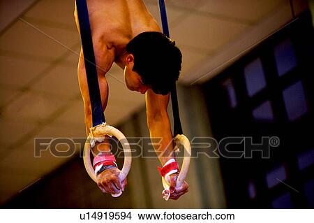 Picture - Young man practicing gymnastics on the gymnastic rings. Fotosearch