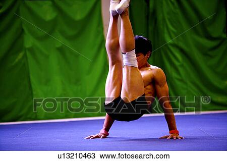 Stock Image - Young man practicing gymnastics on the floor. Fotosearch