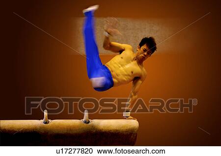 Stock Image - Young man practicing gymnastics on the pommel horse. Fotosearch