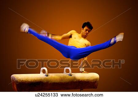 Stock Image - Young man practicing gymnastics on the pommel horse. Fotosearch