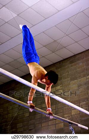 Young man practicing gymnastics on the parallel bars View Large Photo Image Stock Image - Young man practicing gymnastics on the parallel bars. Fotosearch