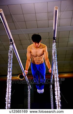 Young man practicing gymnastics on the parallel bars View Large Photo Image Stock Photo - Young man practicing gymnastics on the parallel bars. Fotosearch