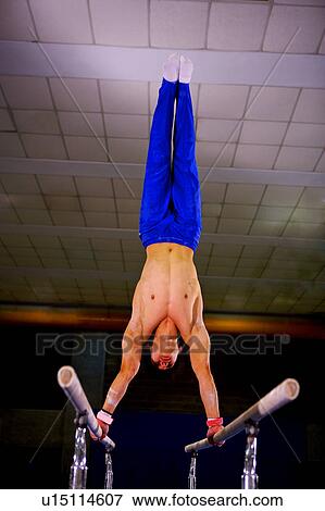 Young man practicing gymnastics on the parallel bars, front view View Large Photo Image Stock Photo - Young man practicing gymnastics on the parallel bars, front view. Fotosearch