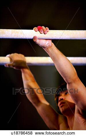Stock Photo - Young man practicing gymnastics on the parallel bars. Fotosearch