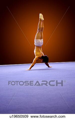 Stock Photo - Young man practicing gymnastics on the floor, headstand. Fotosearch