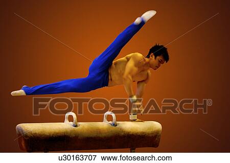 Stock Photo - Young man practicing gymnastics on the pommel horse. Fotosearch