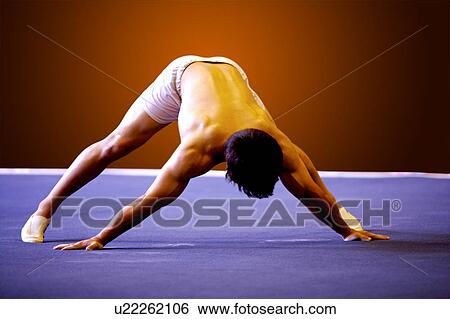 Stock Photograph - Young man practicing gymnastics on the floor. Fotosearch