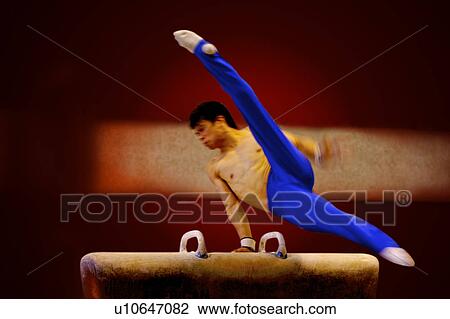 Stock Image - Young man practicing on pommel horse. Fotosearch