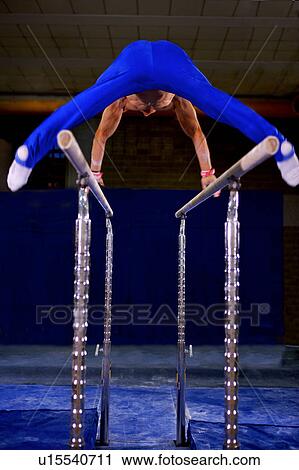 Stock Image - Young man practicing on the parallel bars. Fotosearch