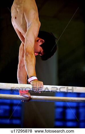 Stock Photo - Young man practicing on the parallel bars, side view. Fotosearch