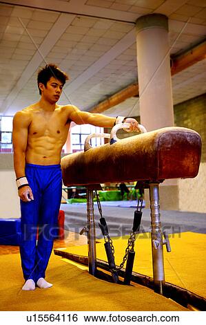 Stock Photograph - Young man preparing for practice on pommel horse. Fotosearch