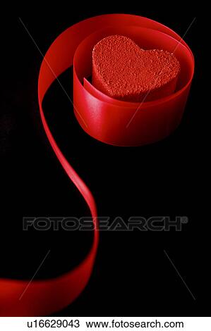 Stock Image - Close-up of a red heart shape object in the red ribbon. Fotosearch