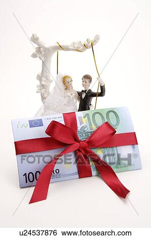 Stock Photograph - Close-up of figurines and paper money with red tied ribbon. Fotosearch