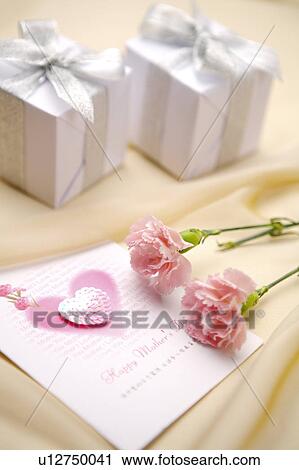 Stock Image - Close-up of two wrapped presents, pink flowers and a greeting card. Fotosearch
