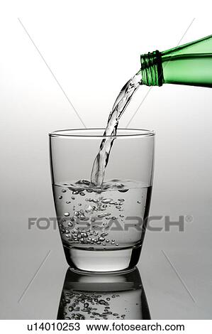 Stock Image - Close-up of a bottle pouring water into a glass. Fotosearch