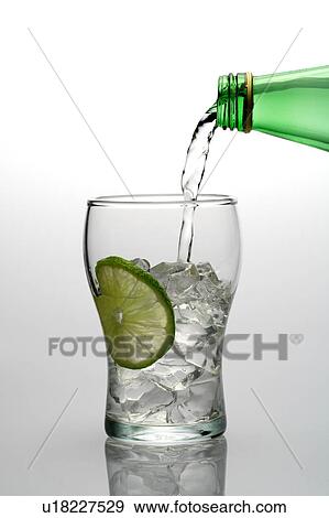 Water pouring into a glass with ice cubes and lemon from a bottle View Large Photo Image Stock Photo - Water pouring into a glass with ice cubes and lemon from a bottle. Fotosearch