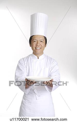 Stock Image - Chef holding the plate and looking at the camera. Fotosearch