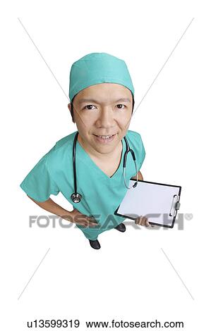 Stock Photo - Doctor in operating gown and holding the clipboard, looking at the camera with arms akimo. Fotosearch