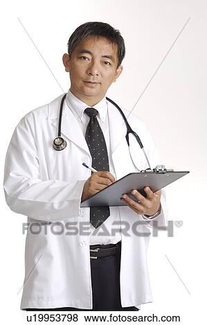 Doctor writing and looking at the camera View Large Photo Image Stock Photo - Doctor writing and looking at the camera. Fotosearch