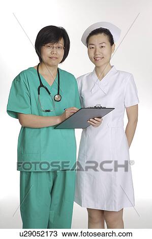 Stock Image - Female doctor and nurse looking at the camera, standing together. Fotosearch