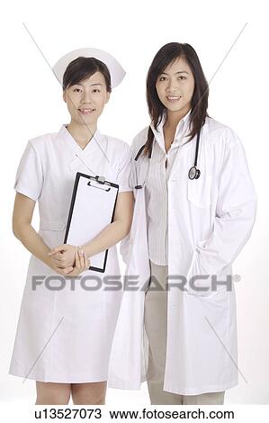 Stock Image - Female doctor and nurse standing together, looking at the camera. Fotosearch