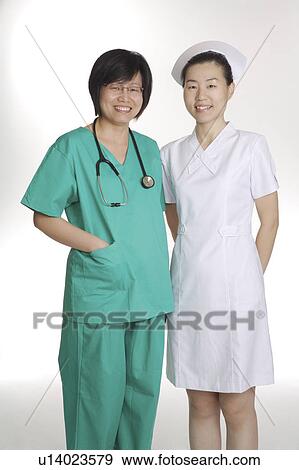 Female doctor and nurse standing together and smiling View Large Photo Image Stock Photo - Female doctor and nurse standing together and smiling. Fotosearch
