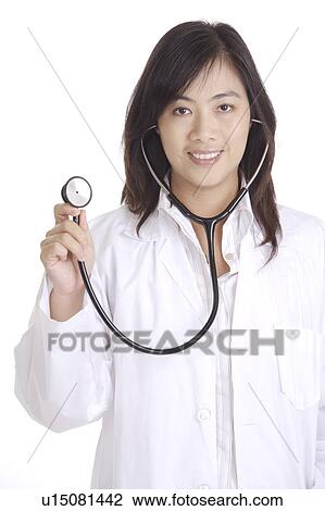 Stock Image - Female doctor holding the stethoscope and smiling at the camera. Fotosearch