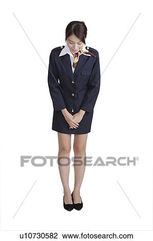 Stock Image - Flight attendant gesturing welcom, bowing with hands folded in front. Fotosearch