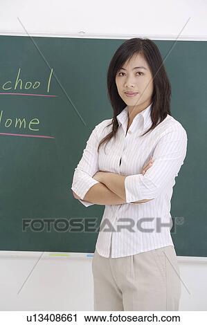 Stock Image - Teacher standing with hands on chest and looking at the camera. Fotosearch