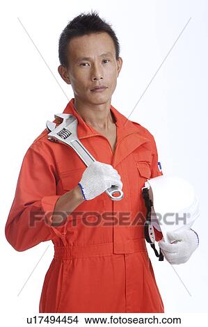 Worker holding a screwdriver and a helmet and looking at the camera View Large Photo Image Picture - Worker holding a screwdriver and a helmet and looking at the camera. Fotosearch