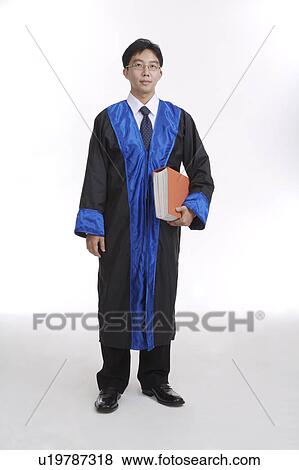 Stock Photo - Young man wearing the robe and holding a book. Fotosearch