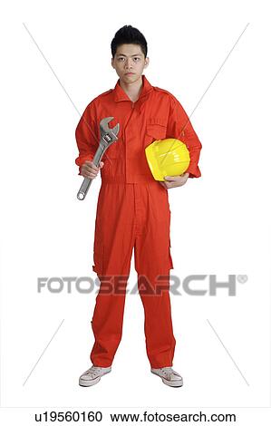 Stock Image - Young mechanic holding a helmet and a screwdriver, looking at the camera. Fotosearch