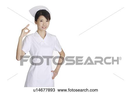 Stock Image - Young nurse gesturing OK and arms akimbo. Fotosearch