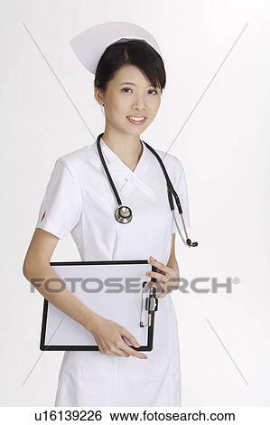 Stock Photograph - Young nurse holding the clipboard and looking at the camera. Fotosearch