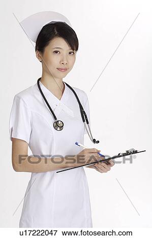 Stock Photo - Young nurse writing and looking at the camera. Fotosearch