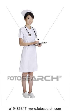 Stock Photo - Young nurse writing on the clipboard and looking at the camera. Fotosearch
