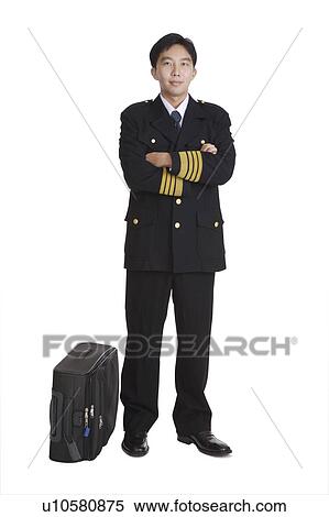Young pilot standing with hands on chest and a suitcase beside View Large Photo Image Stock Photography - Young pilot standing with hands on chest and a suitcase beside. Fotosearch