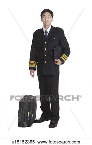 Stock Photography - Young pilot wearing the uniform and holding the uniform cap with a suitcase beside. Fotosearch