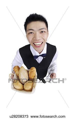 Young waiter holding a basket of bread and looking at the camera View Large Photo Image Stock Image - Young waiter holding a basket of bread and looking at the camera. Fotosearch