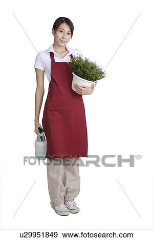 Stock Photo - Young woman holding a potted plant and watering can for gardening. Fotosearch