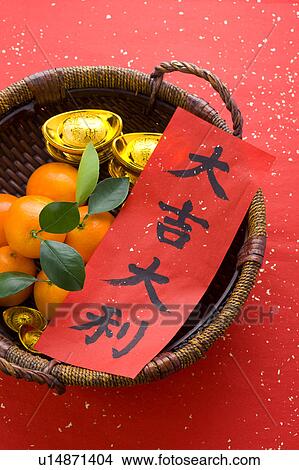 Picture - Close-up of a basket with oranges, gold ingots and Chinese New Year couplets. Fotosearch