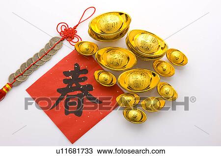 Stock Image - Close-up of gold ingots, Chinese New Year banner and a traditional ornament made of copper coins. Fotosearch