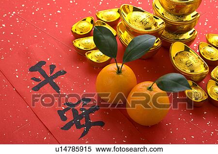 Stock Photography - Close-up of gold ingots, two oranges and Chinese scripts. Fotosearch