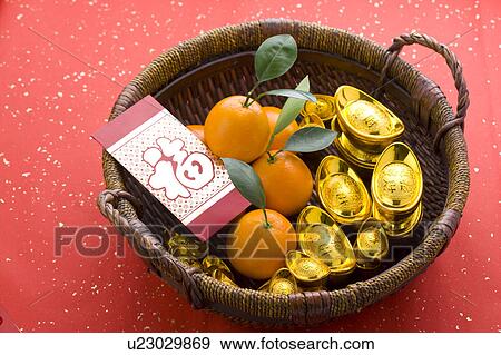 Stock Photo - Close-up of oranges, gold ingots and a card in a bamboo basket. Fotosearch