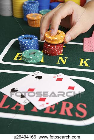 Stock Photograph - Man playing cards, placing bet with gambling chips, close-up. Fotosearch