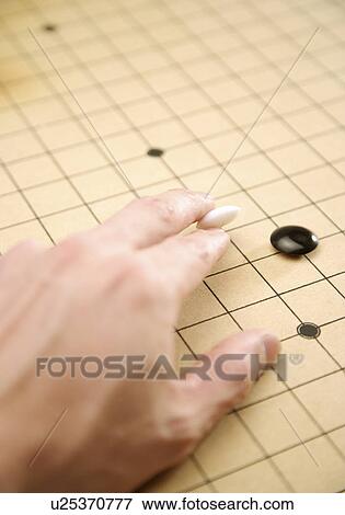 Stock Photo - Man playing Go at Go board. Fotosearch