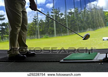 A man hitting golf balls at a driving range View Large Photo Image Picture - A man hitting golf balls at a driving range. Fotosearch