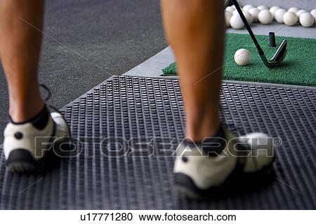 Stock Image - A man hitting golf balls at a driving range. Fotosearch