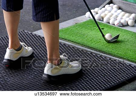 A woman hitting golf balls at a driving range View Large Photo Image Stock Photo - A woman hitting golf balls at a driving range. Fotosearch
