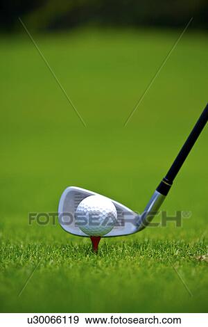 Stock Photo - Golf club against golf ball, ground view, close up. Fotosearch